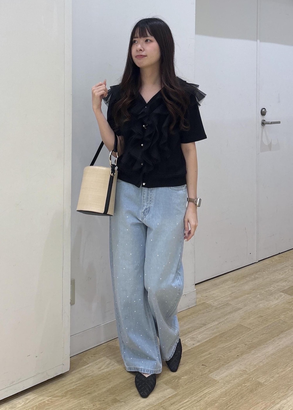 ブルー系のデニムパンツ、ブラック系のサンダル、ブラック系のハンドバッグを着用したレディースの春コーディネートの2枚目の写真