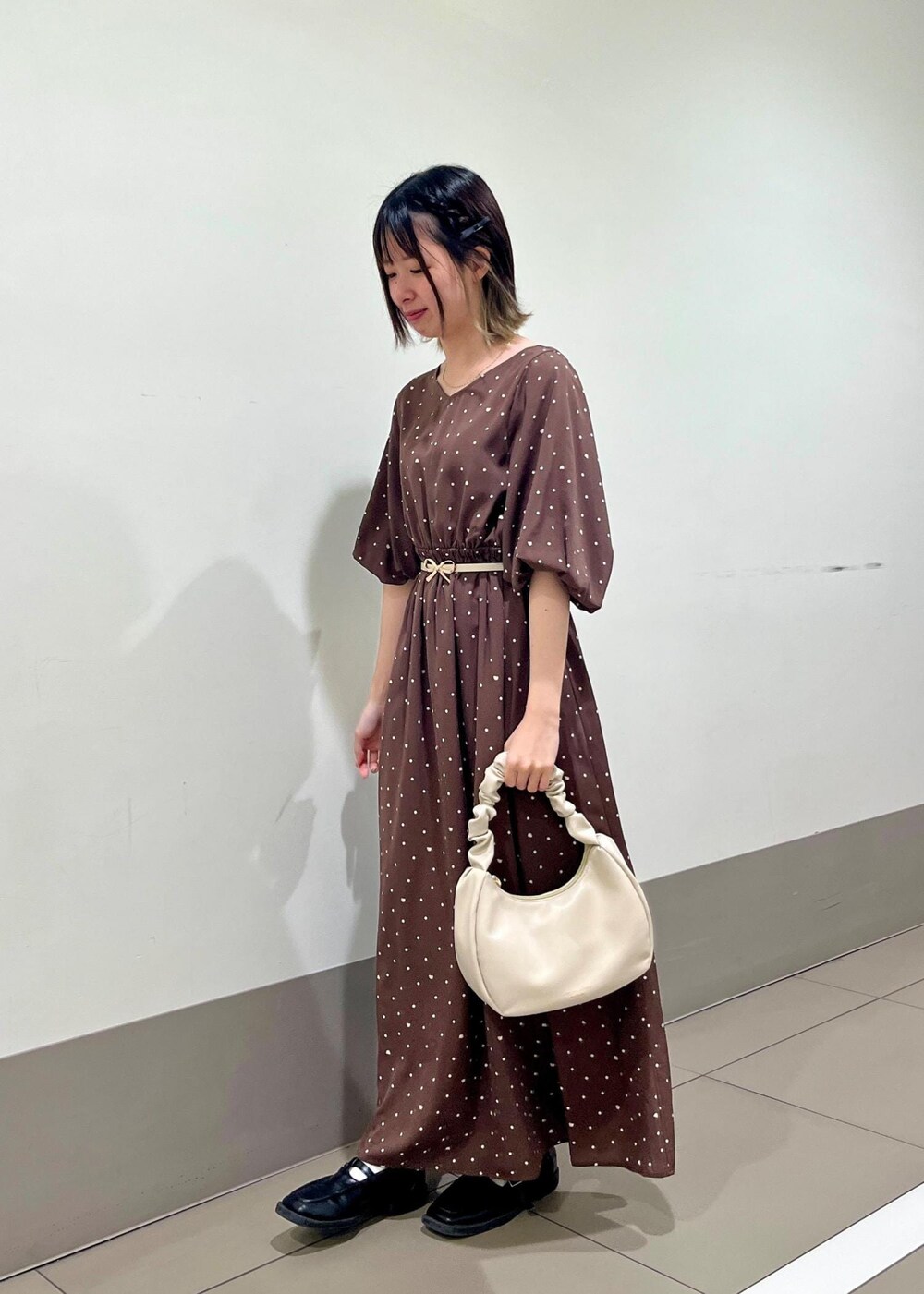 ホワイト系のハンドバッグ、ブラウン系のワンピース、ホワイト系のベルトを着用したレディースの春コーディネートの2枚目の写真