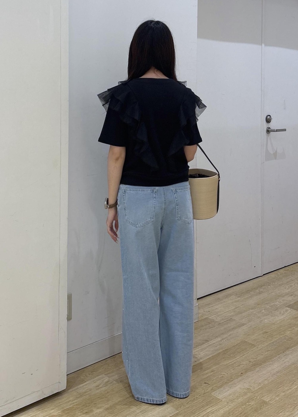 ブルー系のデニムパンツ、ブラック系のサンダル、ブラック系のハンドバッグを着用したレディースの春コーディネートの4枚目の写真