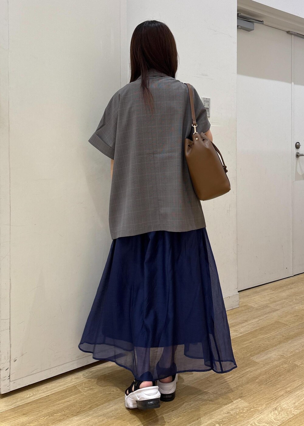 グレー系のテーラードジャケット、ブラウン系のショルダーバッグ、ブルー系のスカートを着用したレディースの夏コーディネートの4枚目の写真
