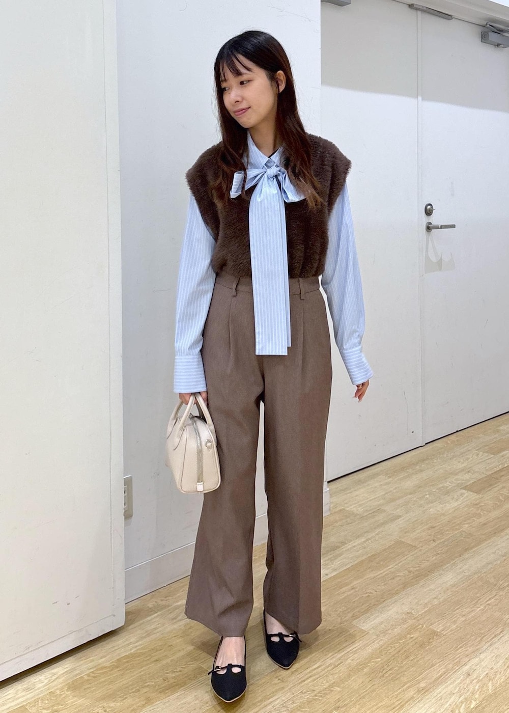 ブルー系のシャツ/ブラウス、ブラウン系のベスト、ベージュ系のスラックスを着用したレディースの秋コーディネートの2枚目の写真