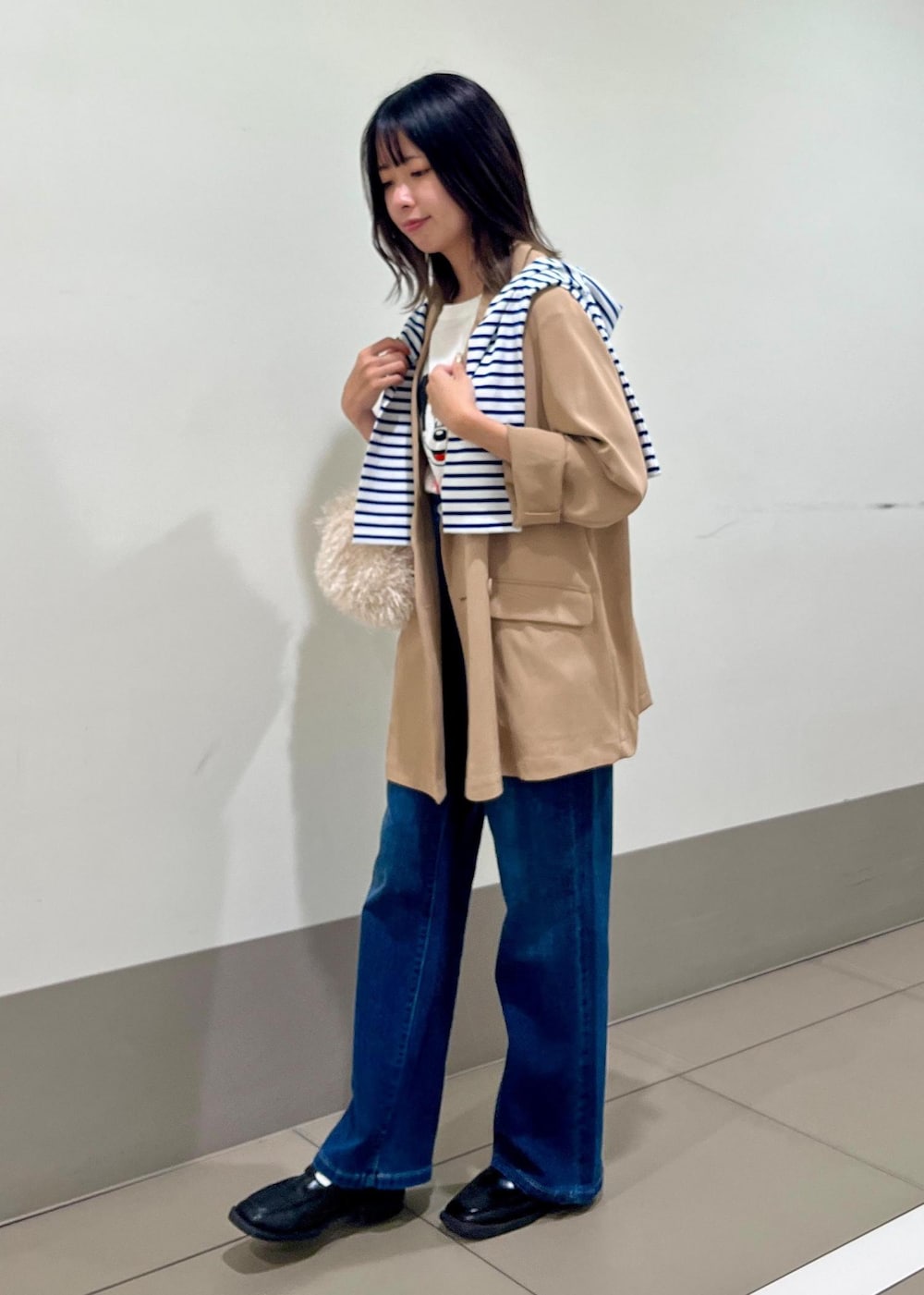 ブルー系のデニムパンツ、ベージュ系のハンドバッグ、ブルー系のTシャツ/カットソーを着用したレディースの秋コーディネートの2枚目の写真