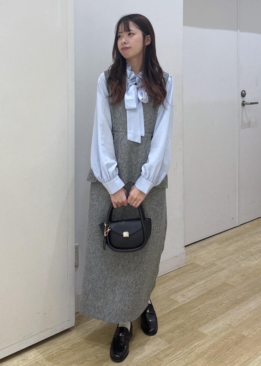 ブラック系のショルダーバッグ、ブラック系のローファー、グレー系のジャンパースカートを着用したレディースの冬コーディネートの2枚目の写真