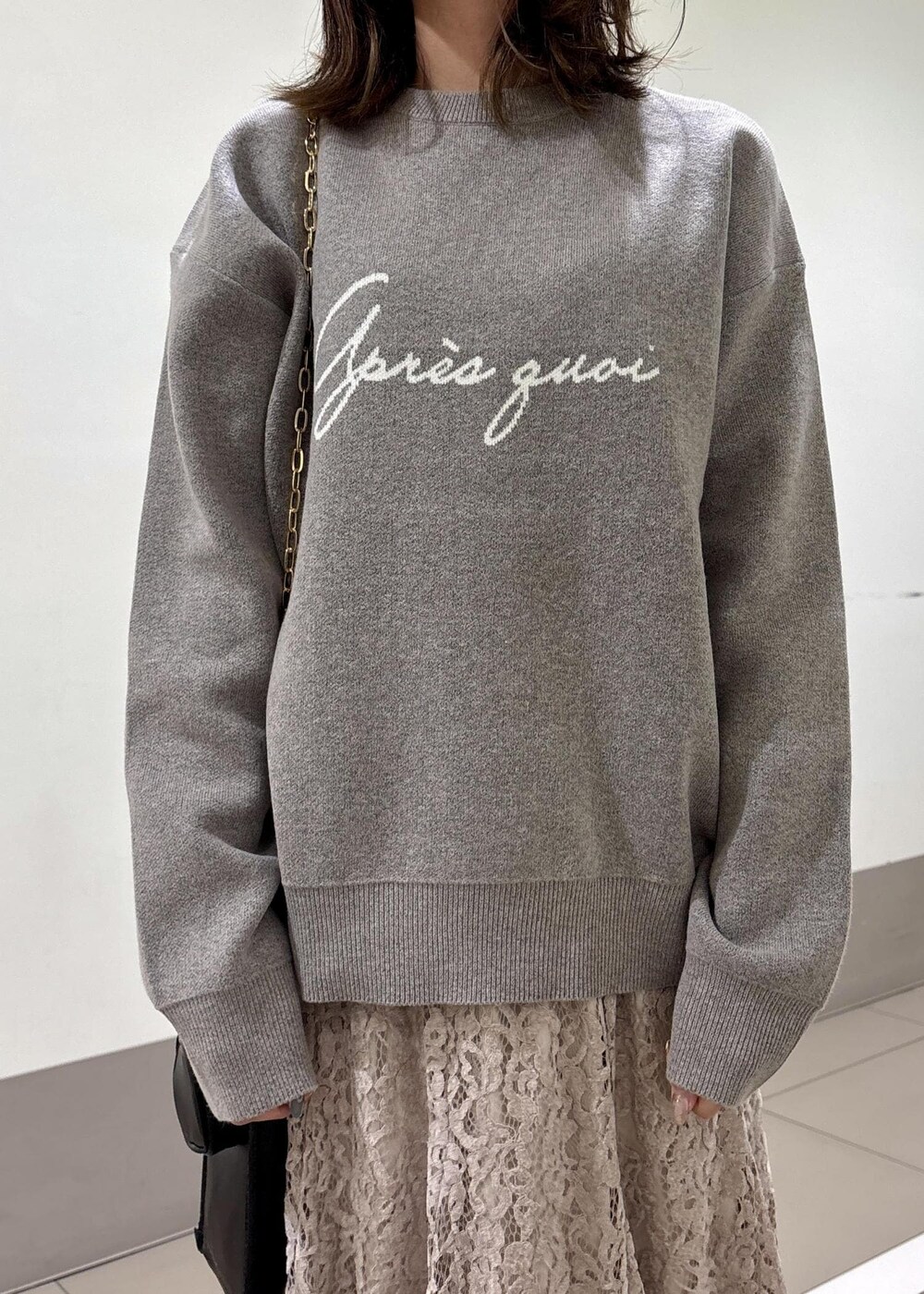 ピンク系のスカート、グレー系のニット/セーター、ブラック系のショルダーバッグを着用したレディースの秋コーディネートの4枚目の写真