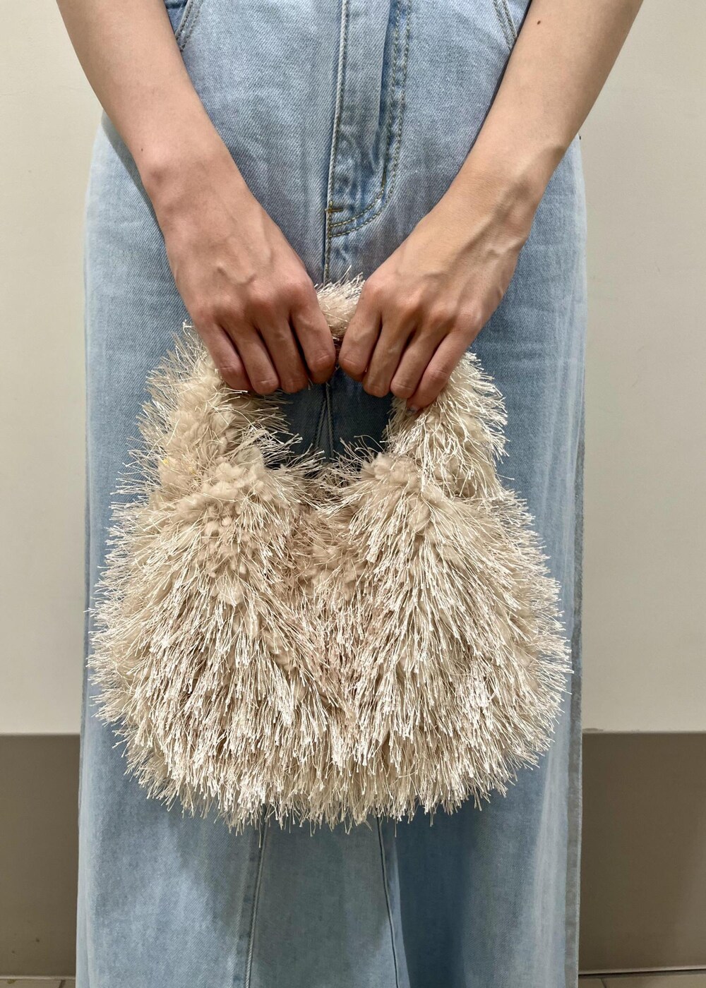 ベージュ系のサンダル、ベージュ系のハンドバッグ、ブルー系のデニムスカートを着用したレディースの秋コーディネートの6枚目の写真