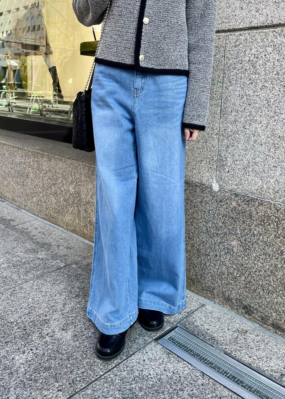 ブラック系のローファー、ブラック系のショルダーバッグ、ブルー系のデニムパンツを着用したレディースの春コーディネートの4枚目の写真