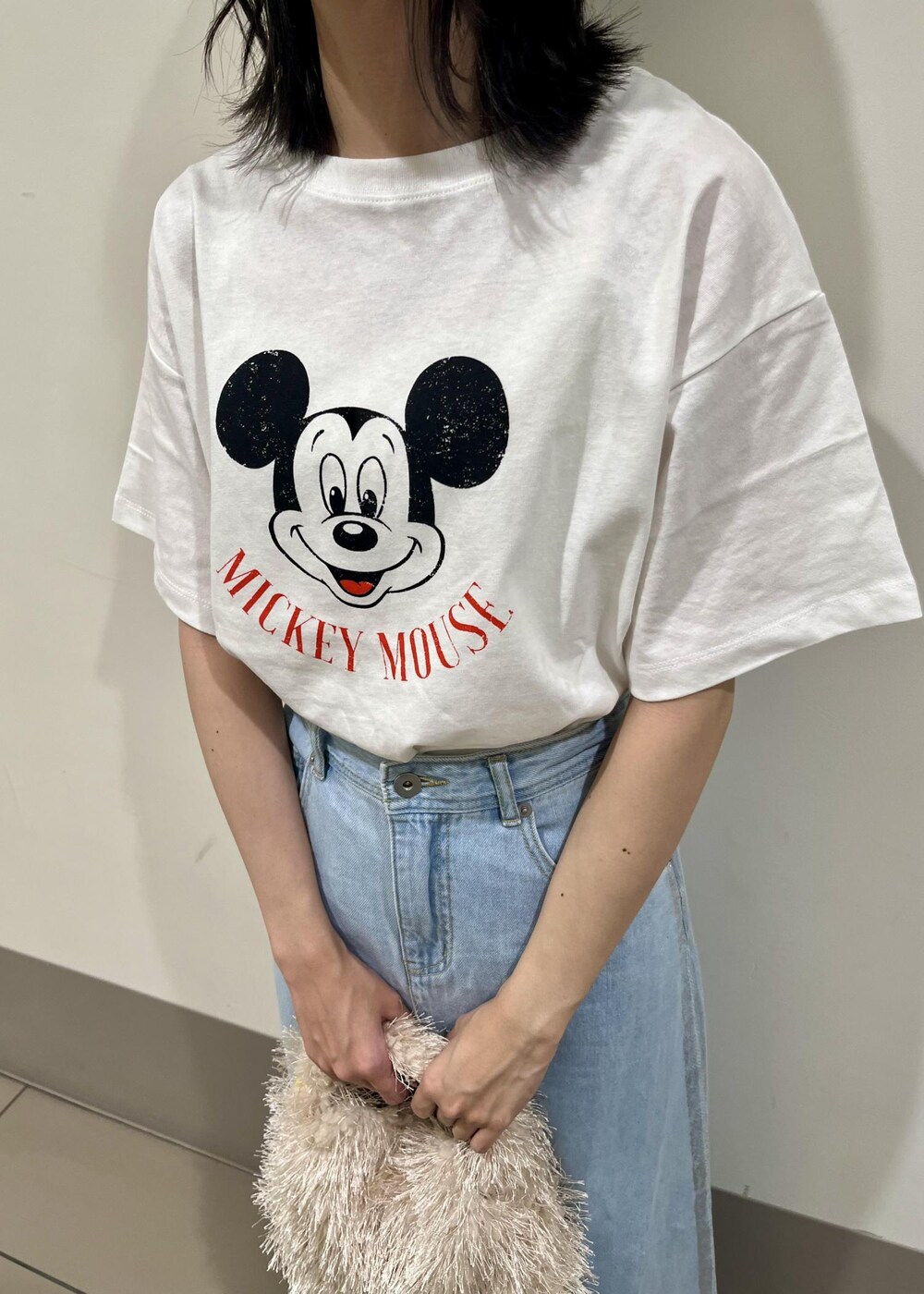 ベージュ系のサンダル、ベージュ系のハンドバッグ、ブルー系のデニムスカートを着用したレディースの秋コーディネートの4枚目の写真