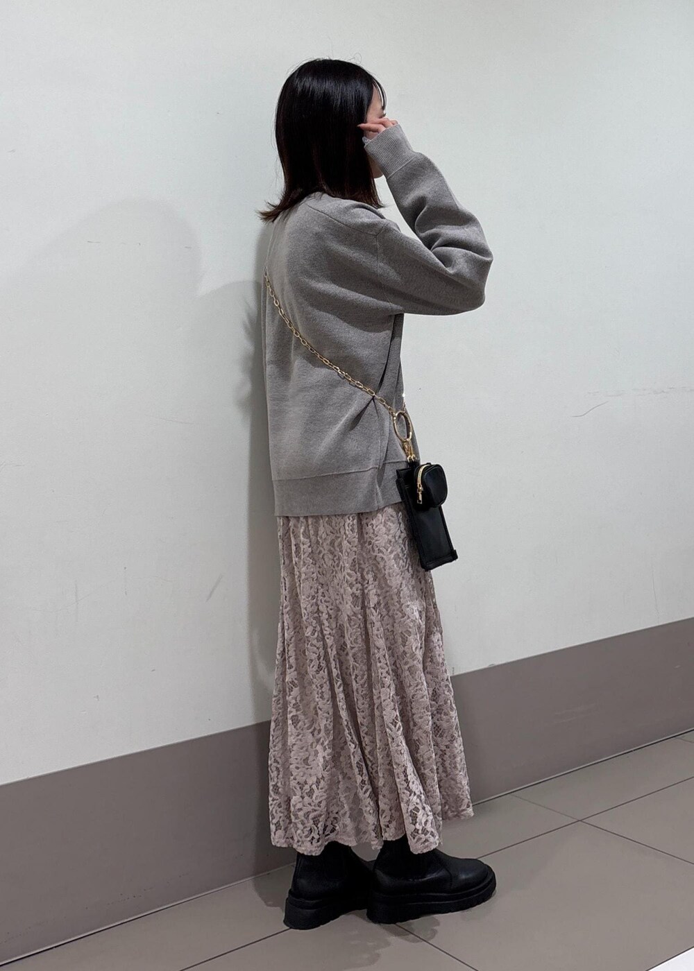 ピンク系のスカート、グレー系のニット/セーター、ブラック系のショルダーバッグを着用したレディースの秋コーディネートの2枚目の写真