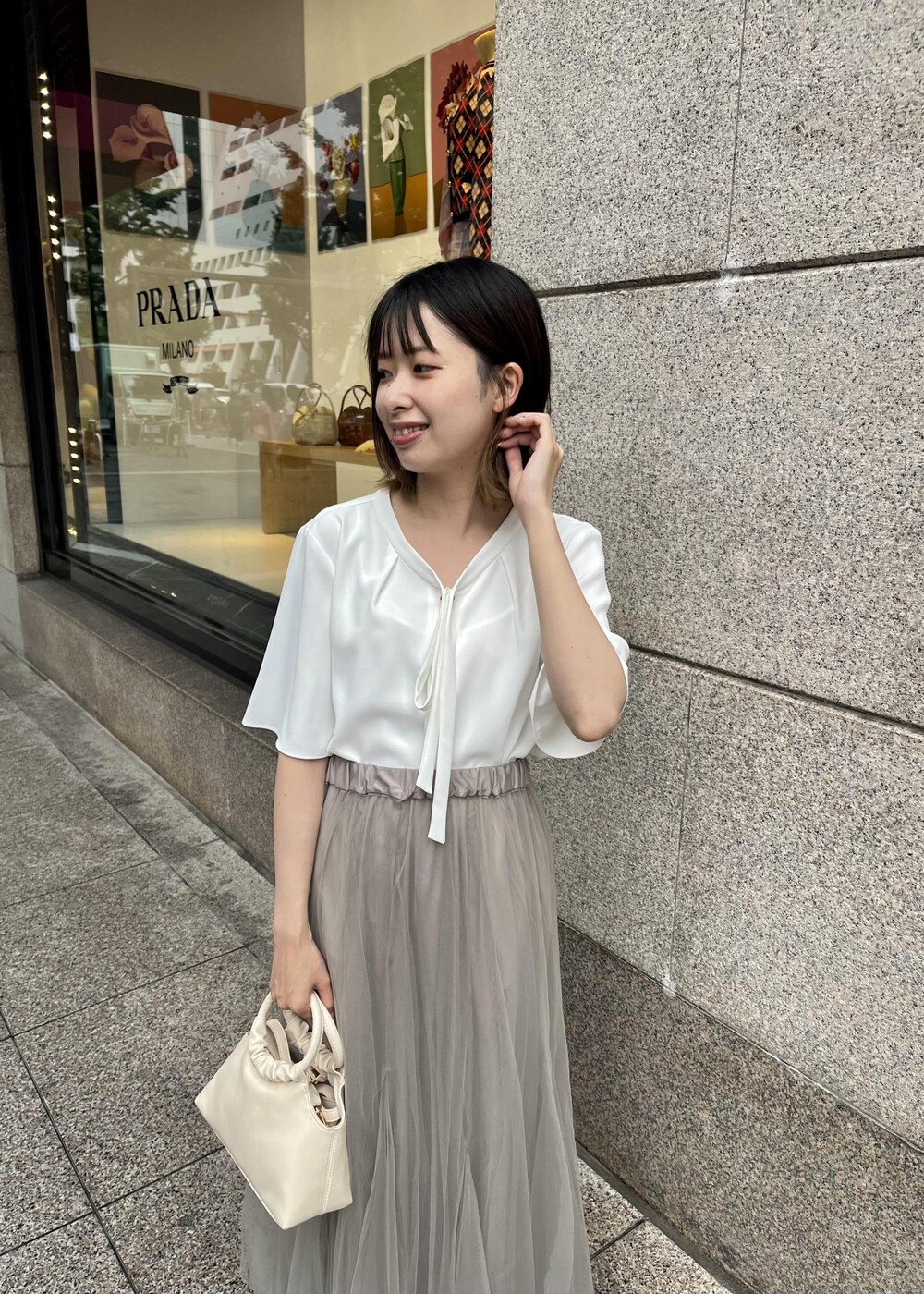 ベージュ系のスカート、ホワイト系のシャツ/ブラウス、ホワイト系のサンダルを着用したレディースの夏コーディネートの3枚目の写真