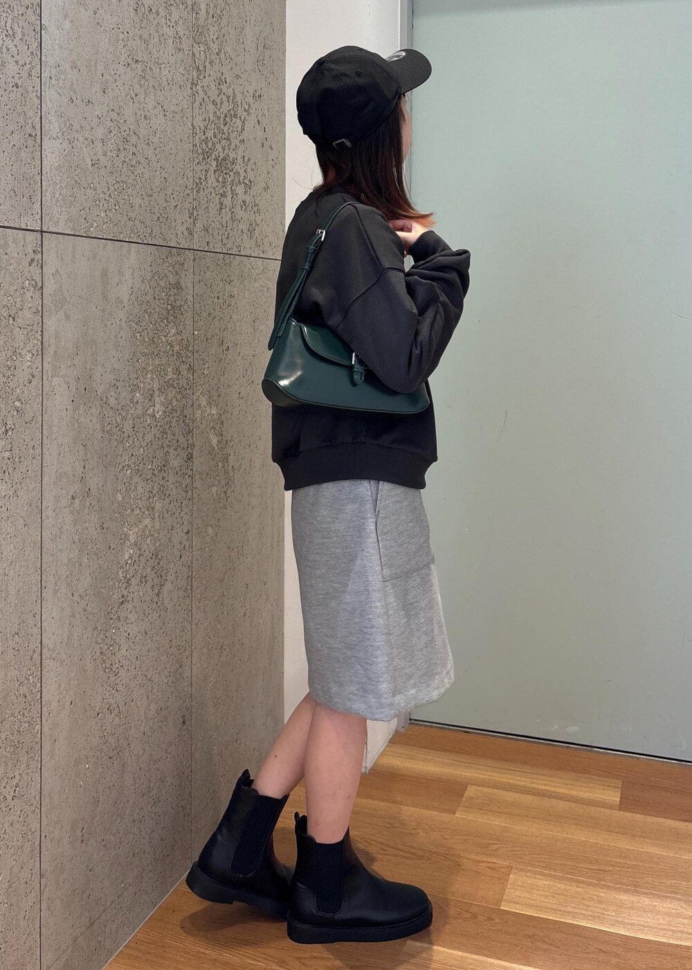 グリーン系のショルダーバッグ、ブラック系のブーツ、グレー系のスカートを着用したレディースの冬コーディネートの3枚目の写真