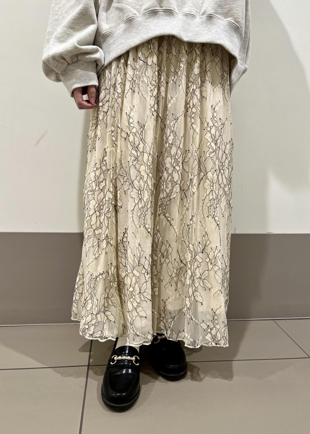 ブラック系のローファー、グレー系のスウェット、ホワイト系のスカートを着用したレディースの春コーディネートの4枚目の写真