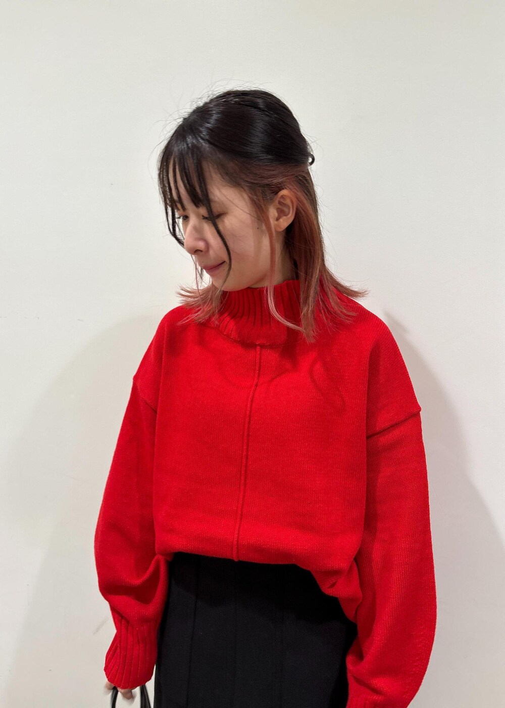 レッド系のニット/セーター、ブラック系のボストンバッグ、ブラック系のスカートを着用したレディースの冬コーディネートの5枚目の写真