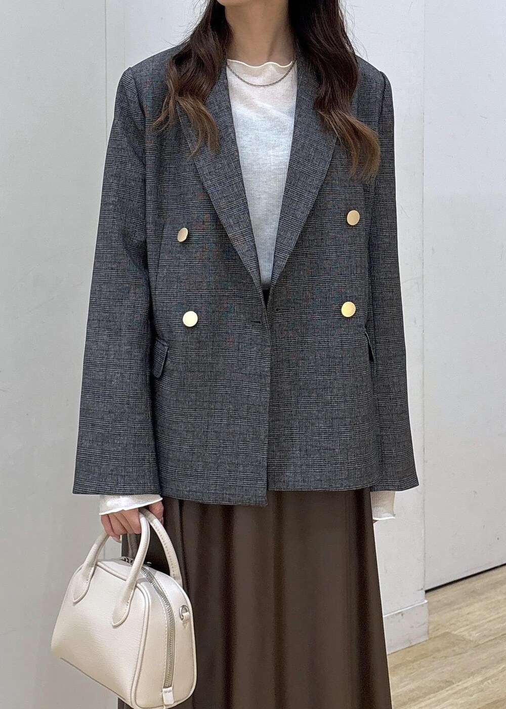 グレー系のテーラードジャケット、ホワイト系のTシャツ/カットソー、ブラウン系のスカートを着用したレディースの秋コーディネートの6枚目の写真