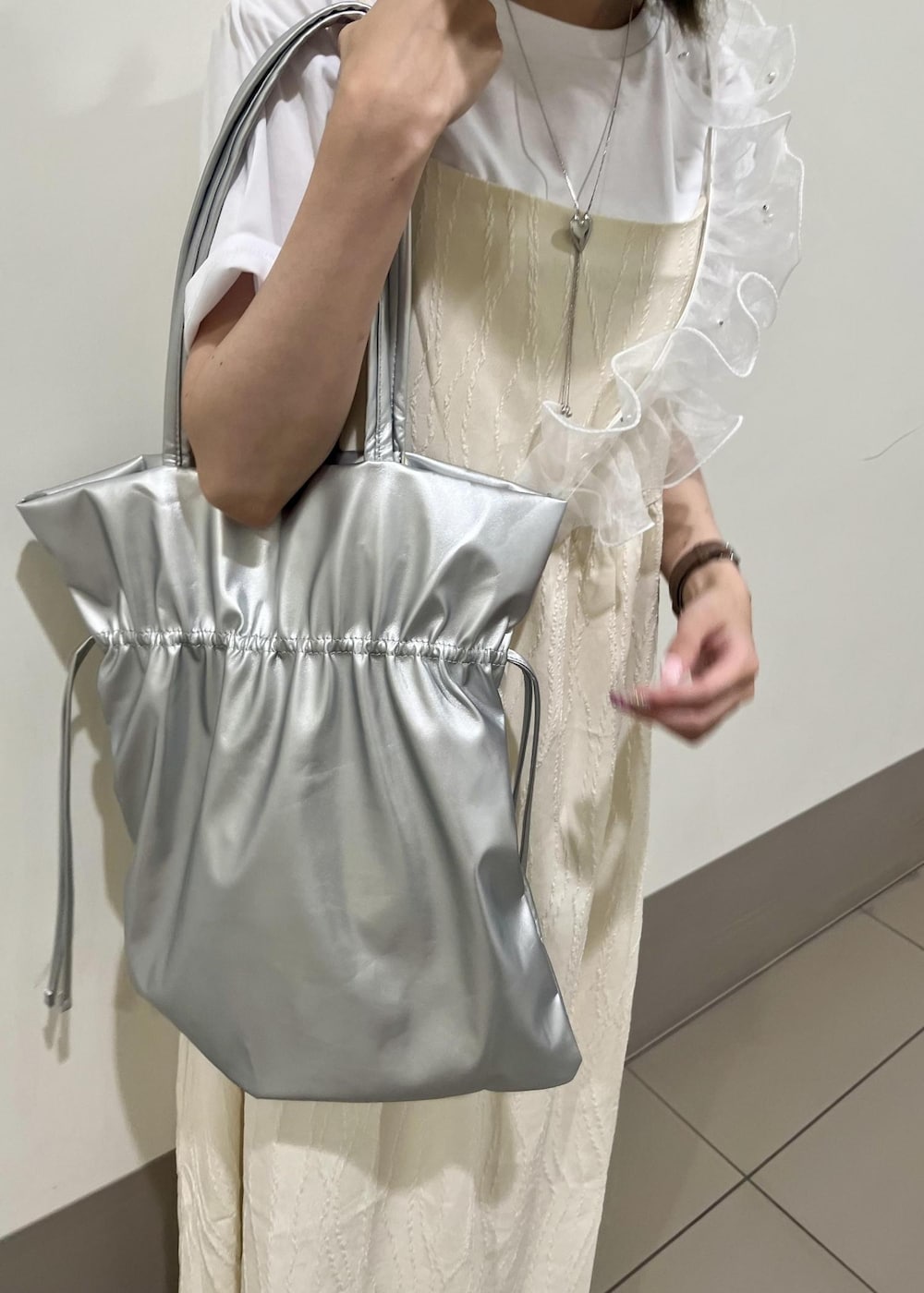 シルバー系のトートバッグ、ホワイト系のワンピース、ホワイト系のTシャツ/カットソーを着用したレディースの夏コーディネートの4枚目の写真