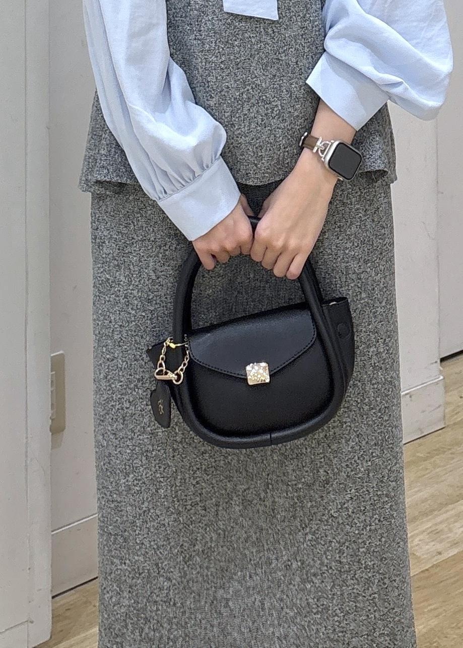 ブラック系のショルダーバッグ、ブラック系のローファー、グレー系のジャンパースカートを着用したレディースの冬コーディネートの6枚目の写真