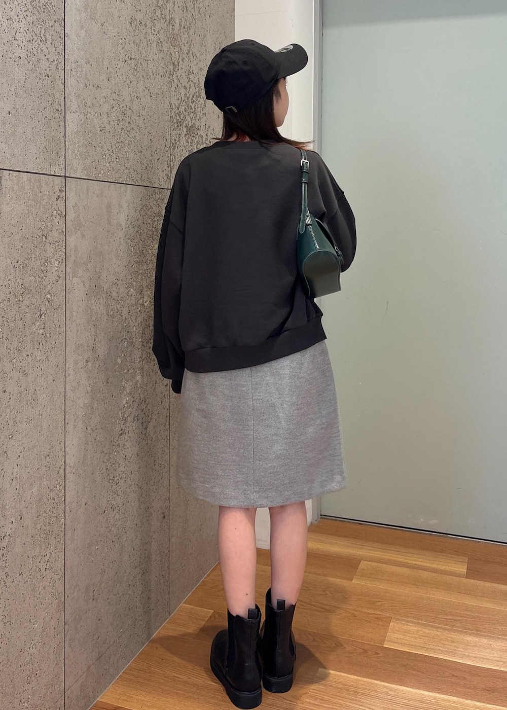 グリーン系のショルダーバッグ、ブラック系のブーツ、グレー系のスカートを着用したレディースの冬コーディネートの2枚目の写真