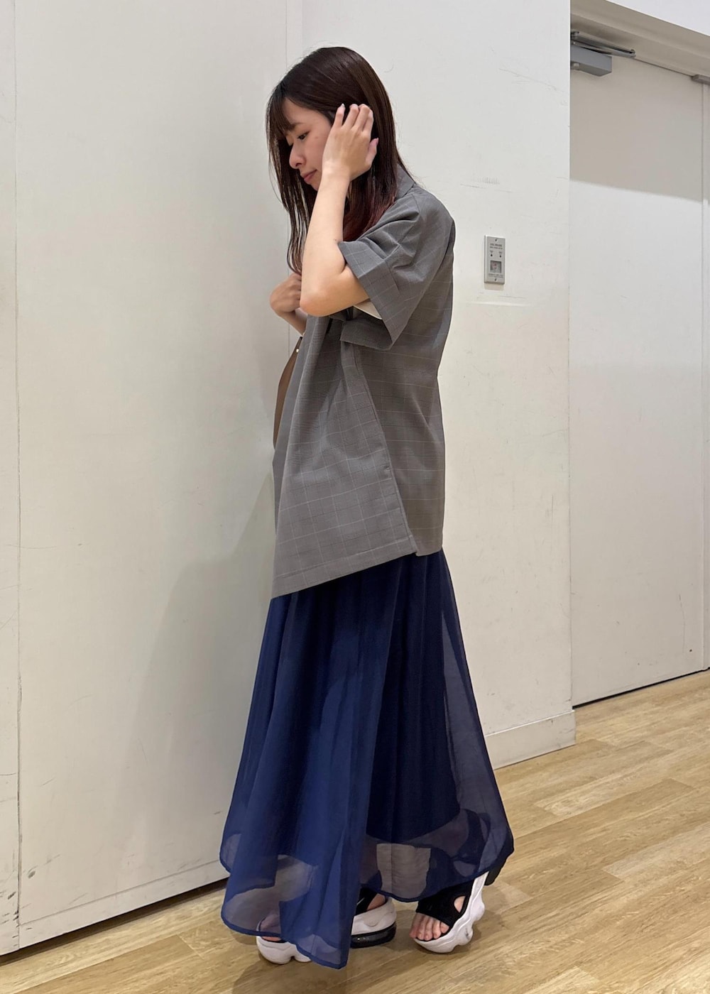 グレー系のテーラードジャケット、ブラウン系のショルダーバッグ、ブルー系のスカートを着用したレディースの夏コーディネートの5枚目の写真