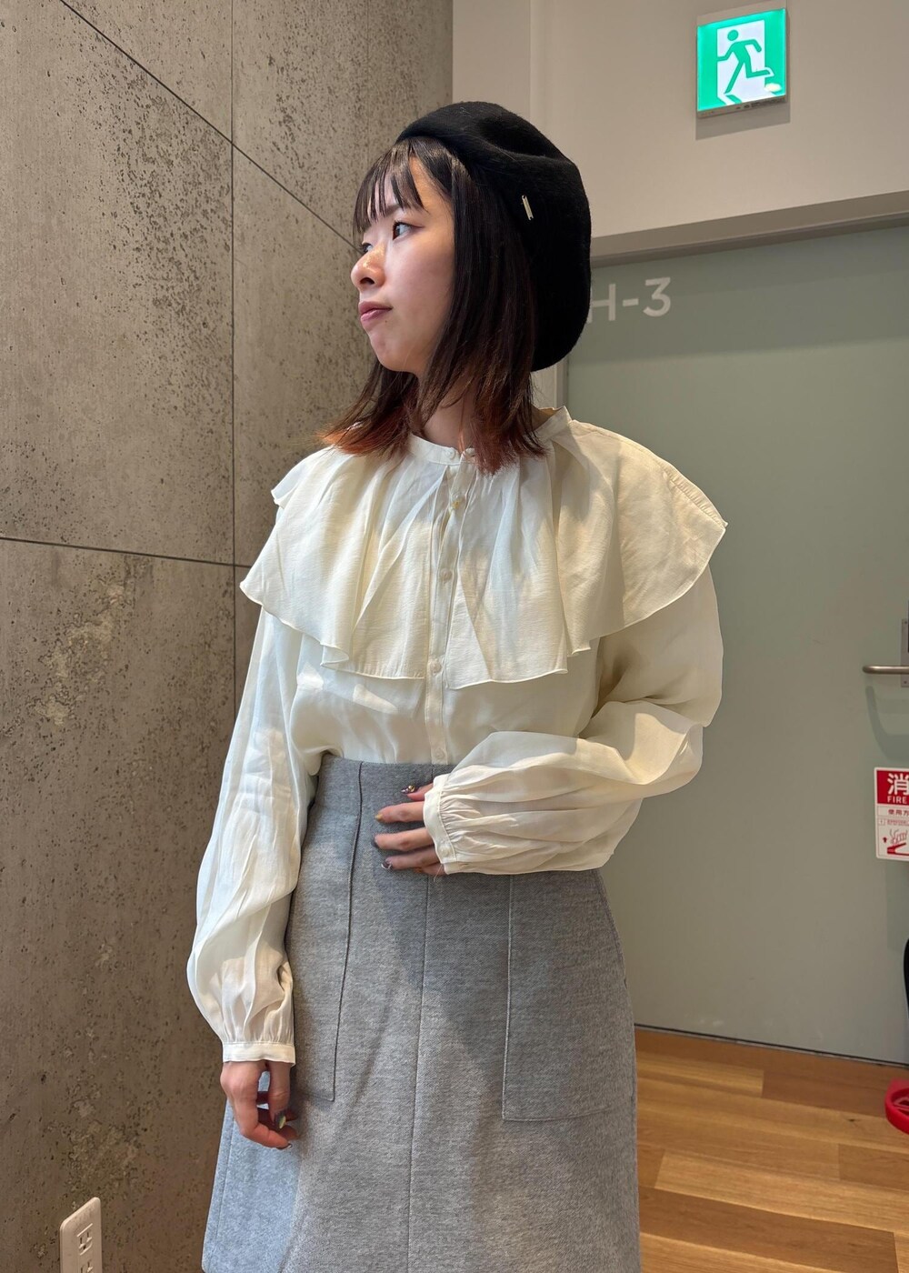 グレー系のスカート、ホワイト系のシャツ/ブラウス、ブラック系のブーツを着用したレディースの冬コーディネートの4枚目の写真