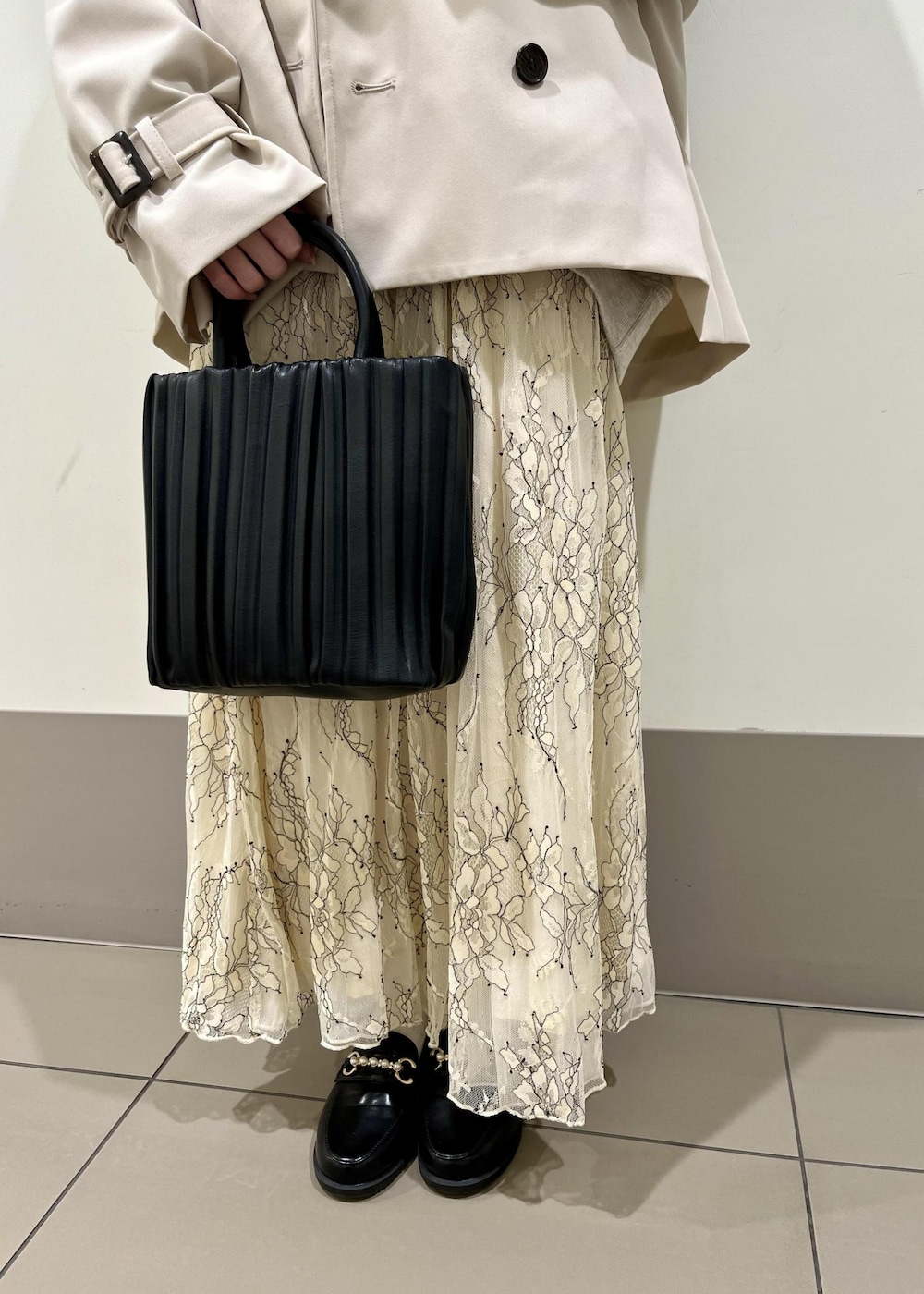 ブラック系のローファー、ホワイト系のスカート、ベージュ系のトレンチコートを着用したレディースの春コーディネートの7枚目の写真