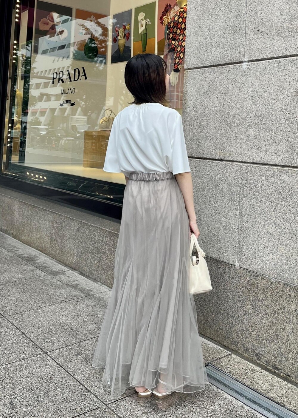 ベージュ系のスカート、ホワイト系のシャツ/ブラウス、ホワイト系のサンダルを着用したレディースの夏コーディネートの2枚目の写真