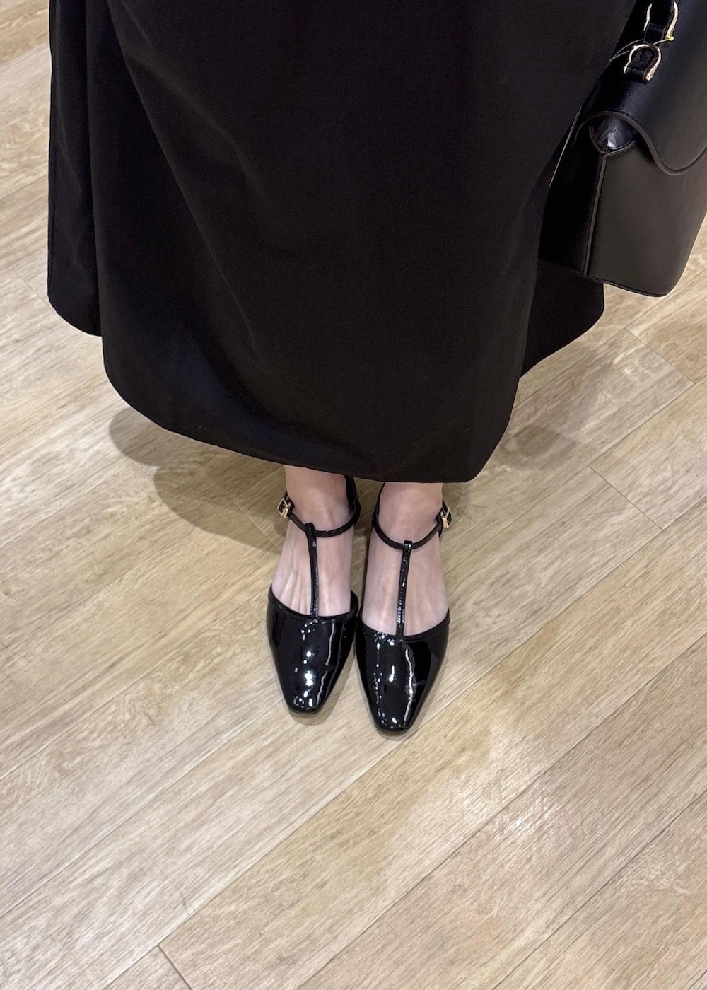 ブラック系のショルダーバッグ、ブラック系のパンプス、ホワイト系のワンピースを着用したレディースの春コーディネートの7枚目の写真
