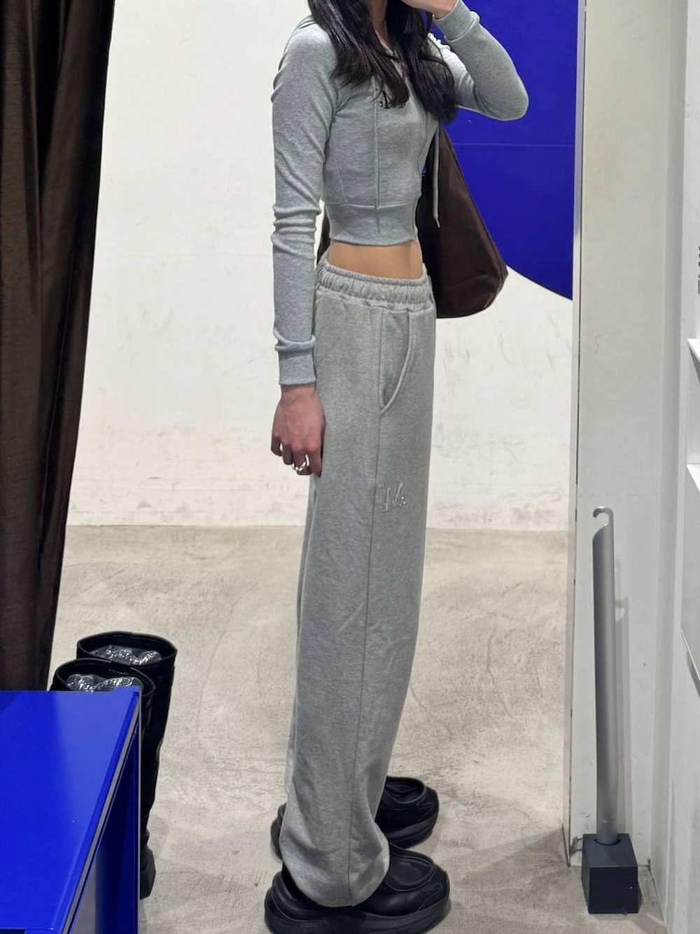 ブラウン系のショルダーバッグ、グレー系のパーカー、グレー系のスウェットパンツを着用したレディースの冬コーディネートの2枚目の写真