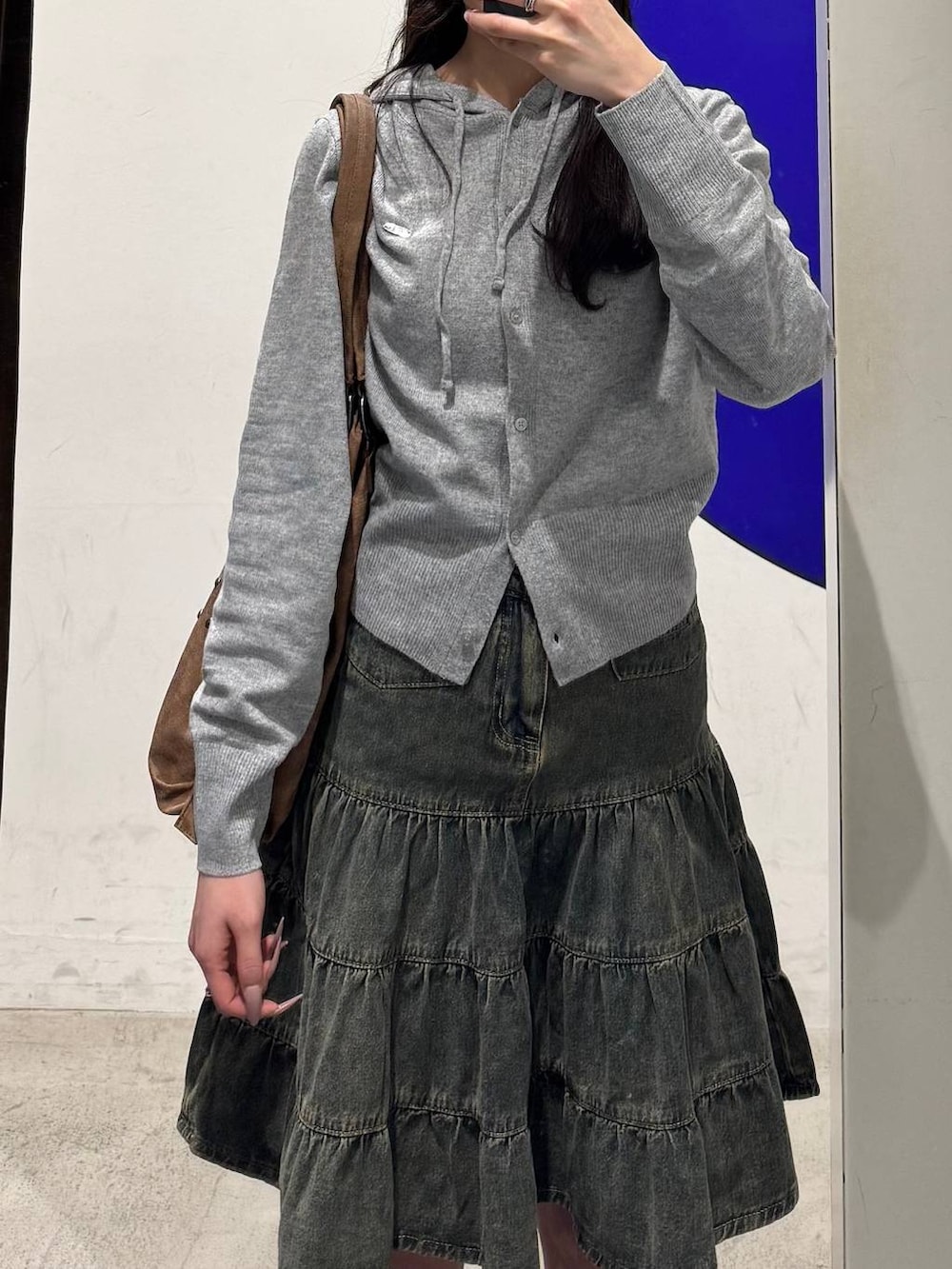 ブラック系のブーツ、グレー系のニット/セーター、ブルー系のデニムスカートを着用したレディースの冬コーディネートの3枚目の写真