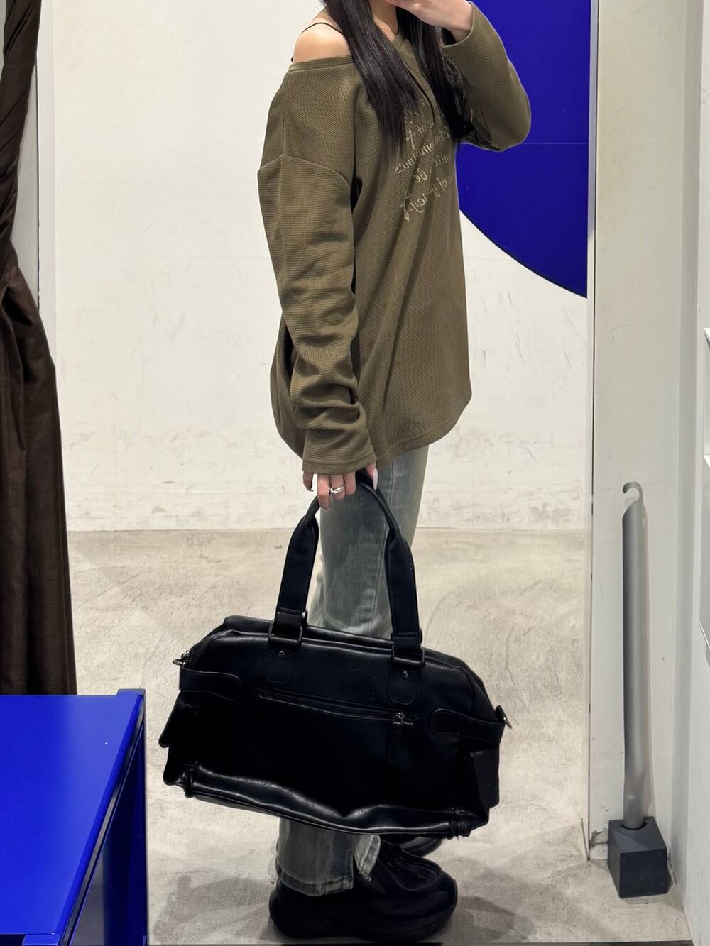ブルー系のデニムパンツ、グリーン系のTシャツ/カットソー、ブラック系のハンドバッグを着用したレディースの冬コーディネートの2枚目の写真