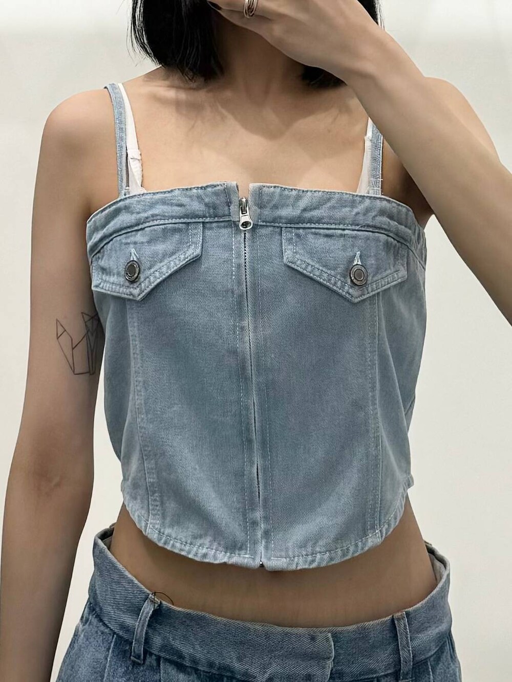 ブルー系のチューブトップ、ブルー系のデニムパンツ、ブルー系のトートバッグを着用したレディースの夏コーディネートの3枚目の写真