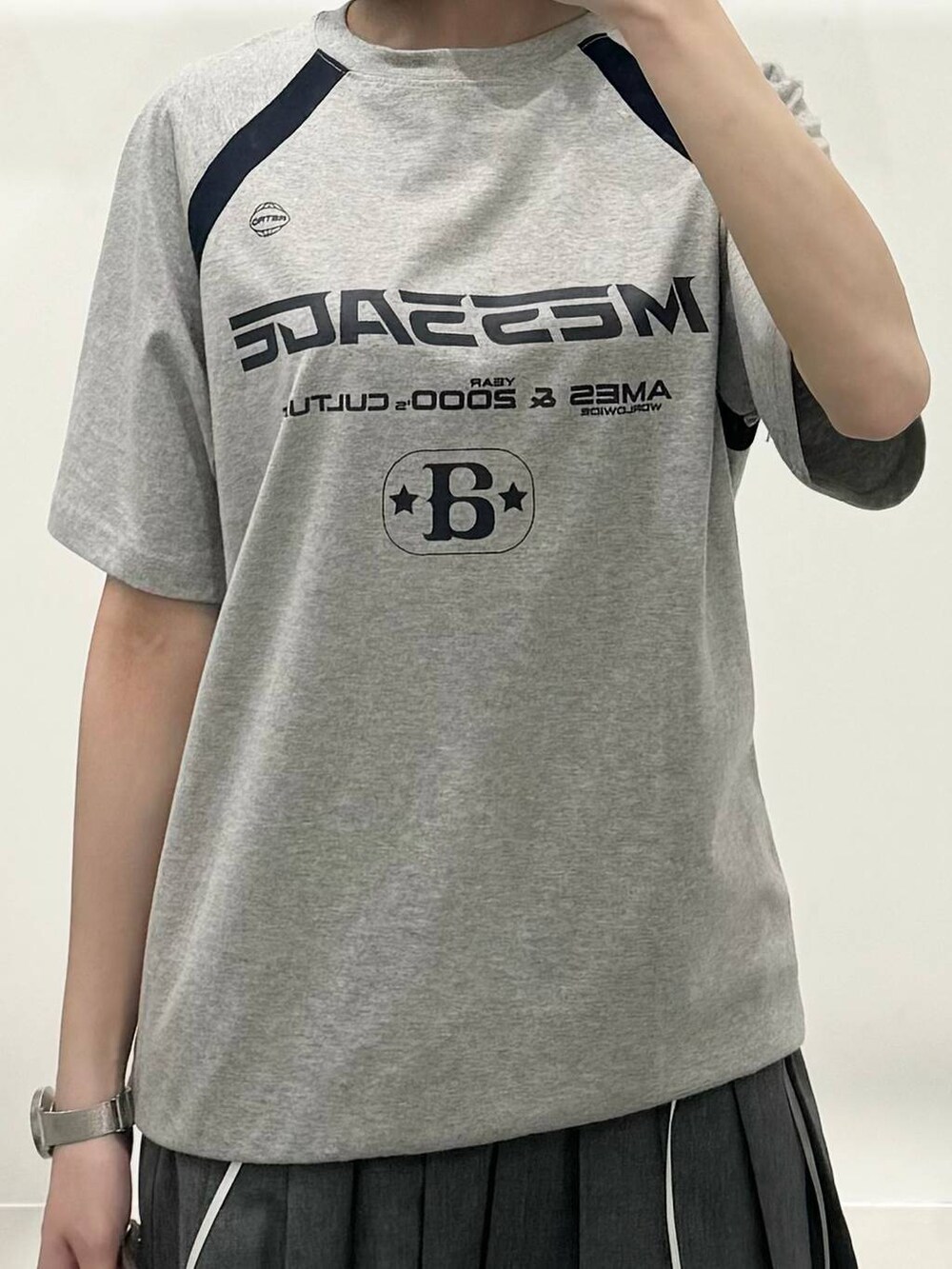 グレー系のTシャツ/カットソー、ブラック系のブーツ、グレー系のスカートを着用したレディースの春コーディネートの3枚目の写真
