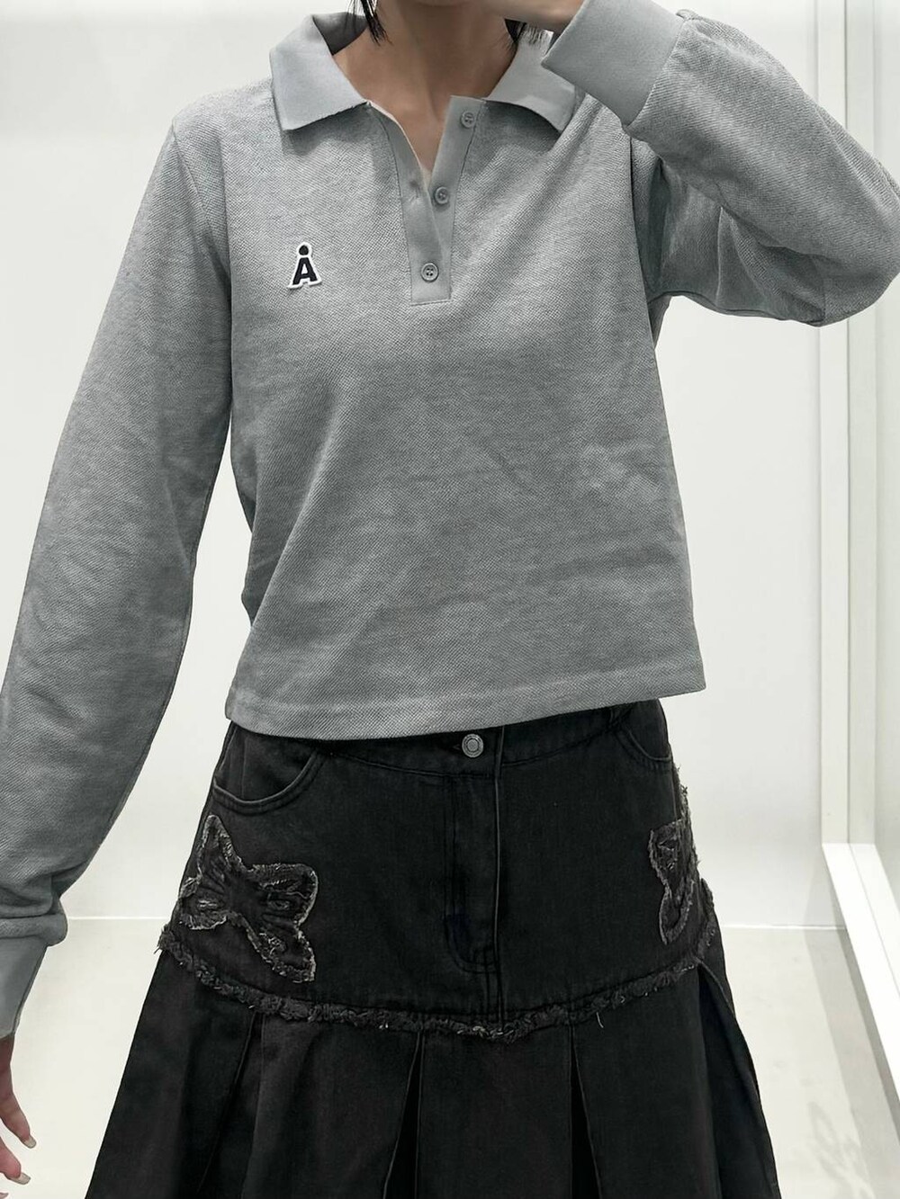 ブラック系のデニムスカート、グレー系のポロシャツを着用したレディースの秋コーディネートの3枚目の写真