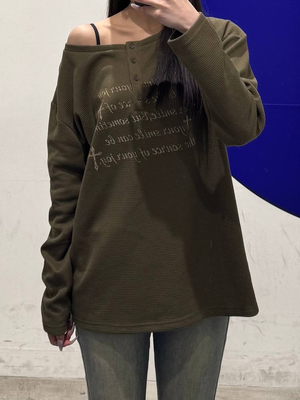 ブルー系のデニムパンツ、グリーン系のTシャツ/カットソー、ブラック系のハンドバッグを着用したレディースの冬コーディネートの3枚目の写真