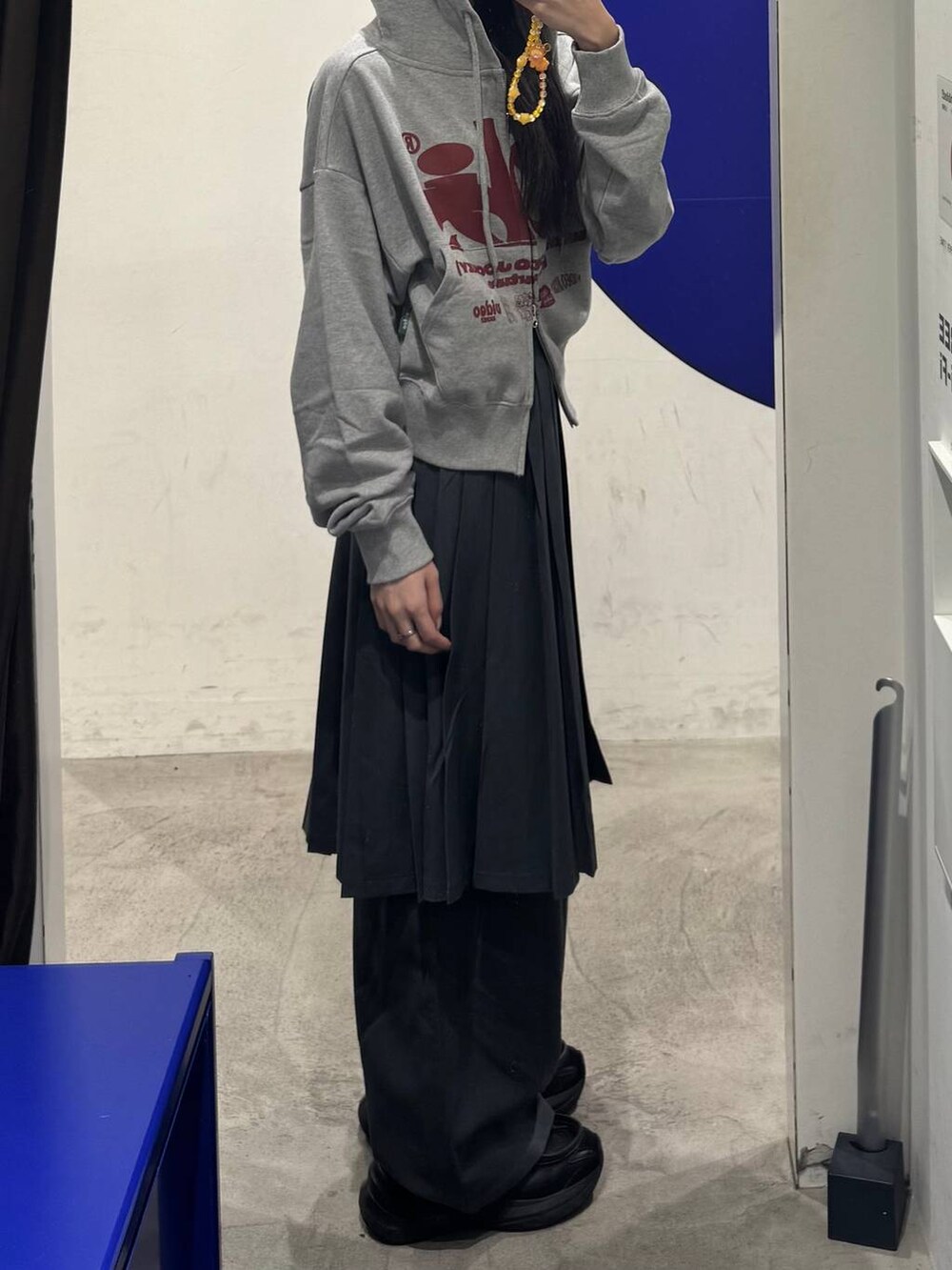 グレー系のパーカー、グレー系のスラックス、グレー系のスカートを着用したレディースの秋コーディネートの2枚目の写真