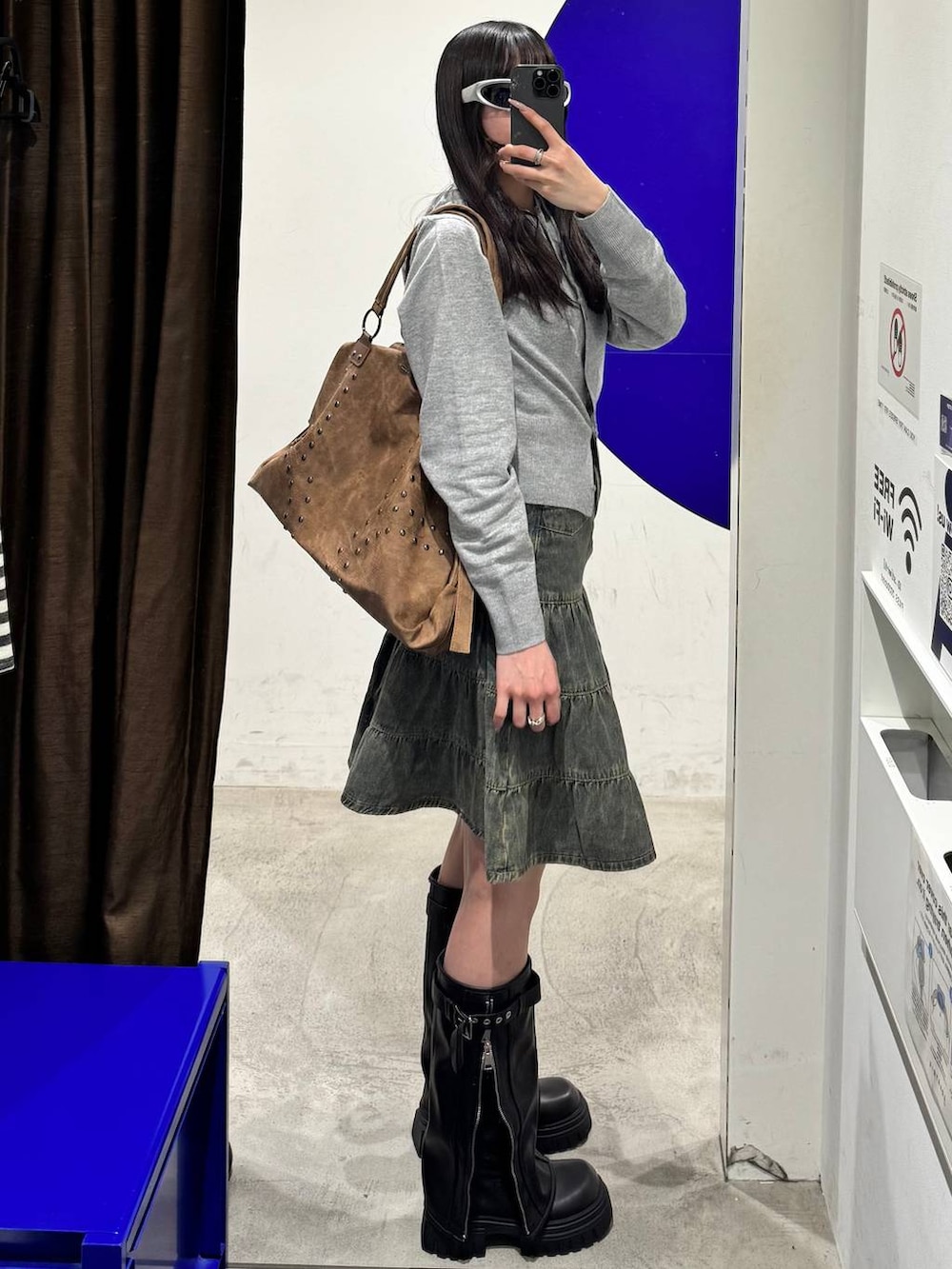 ブラック系のブーツ、グレー系のニット/セーター、ブルー系のデニムスカートを着用したレディースの冬コーディネートの2枚目の写真