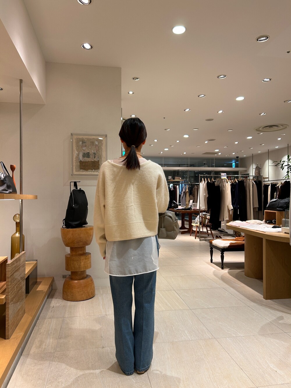 ホワイト系のニット/セーター、ホワイト系のシャツ/ブラウス、ブルー系のデニムパンツを着用したレディースの秋コーディネートの4枚目の写真