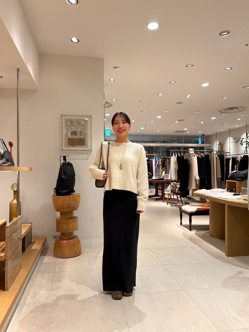 ホワイト系のニット/セーター、ホワイト系のシャツ/ブラウス、ブルー系のデニムパンツを着用したレディースの秋コーディネートの3枚目の写真