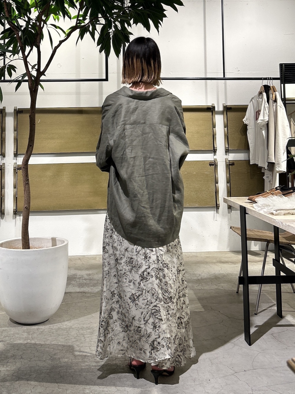 ホワイト系のワンピース、グリーン系のベスト、ブラック系のショルダーバッグを着用したレディースの春コーディネートの3枚目の写真