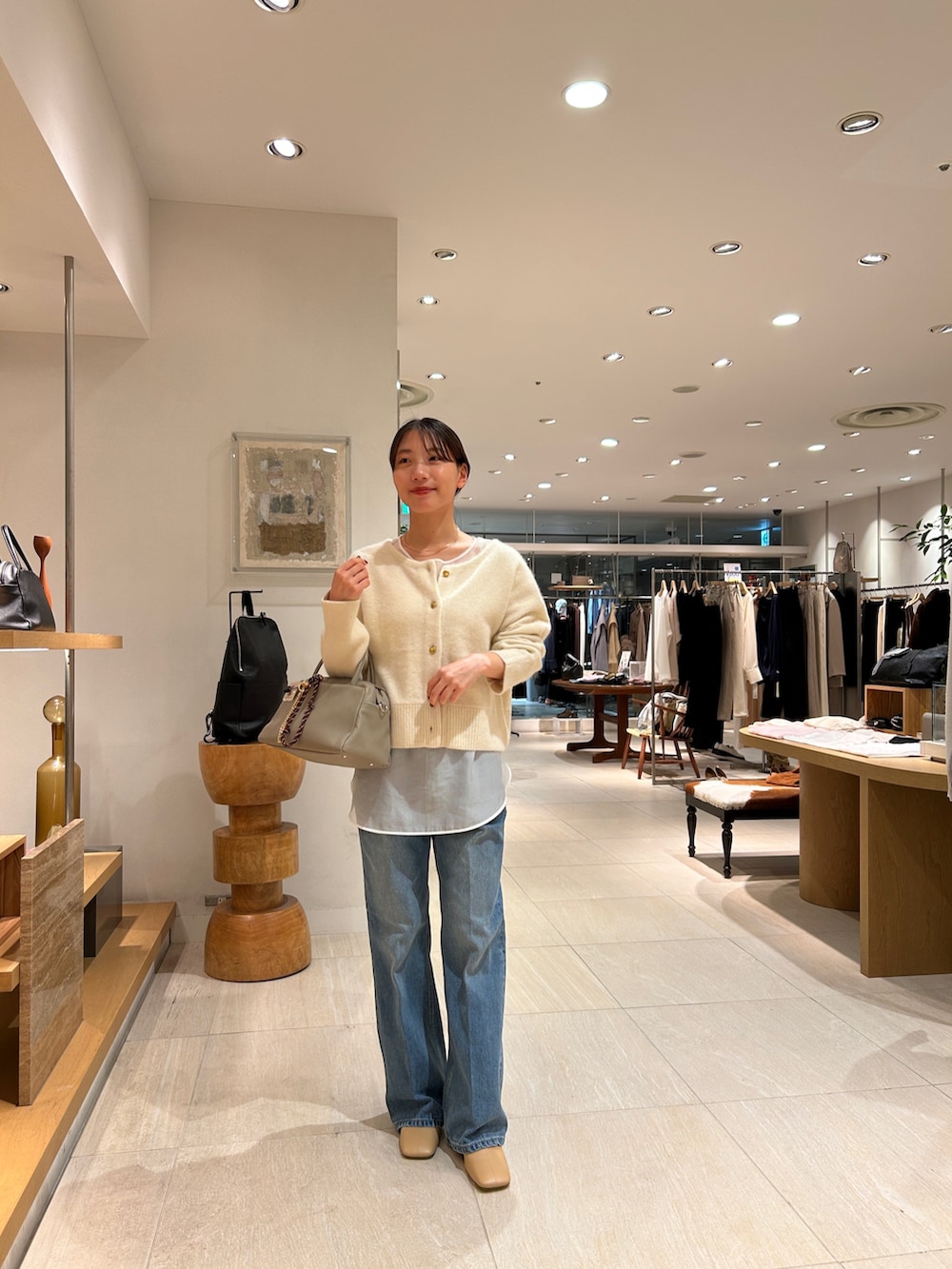 ホワイト系のニット/セーター、ホワイト系のシャツ/ブラウス、ブルー系のデニムパンツを着用したレディースの秋コーディネートの2枚目の写真