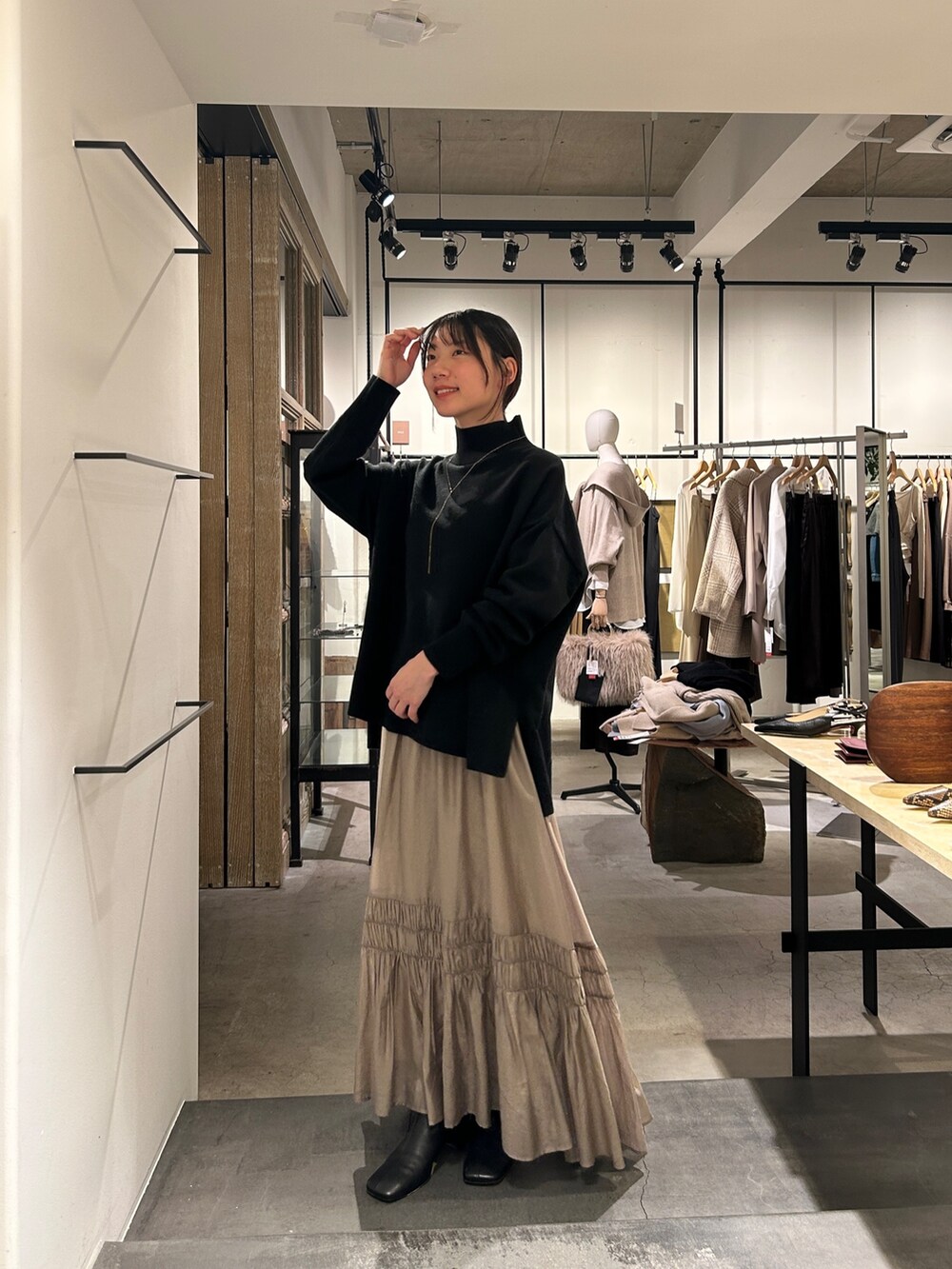 ブラック系のニット/セーター、ベージュ系のスカート、ブラック系のブーツを着用したレディースの冬コーディネートの2枚目の写真