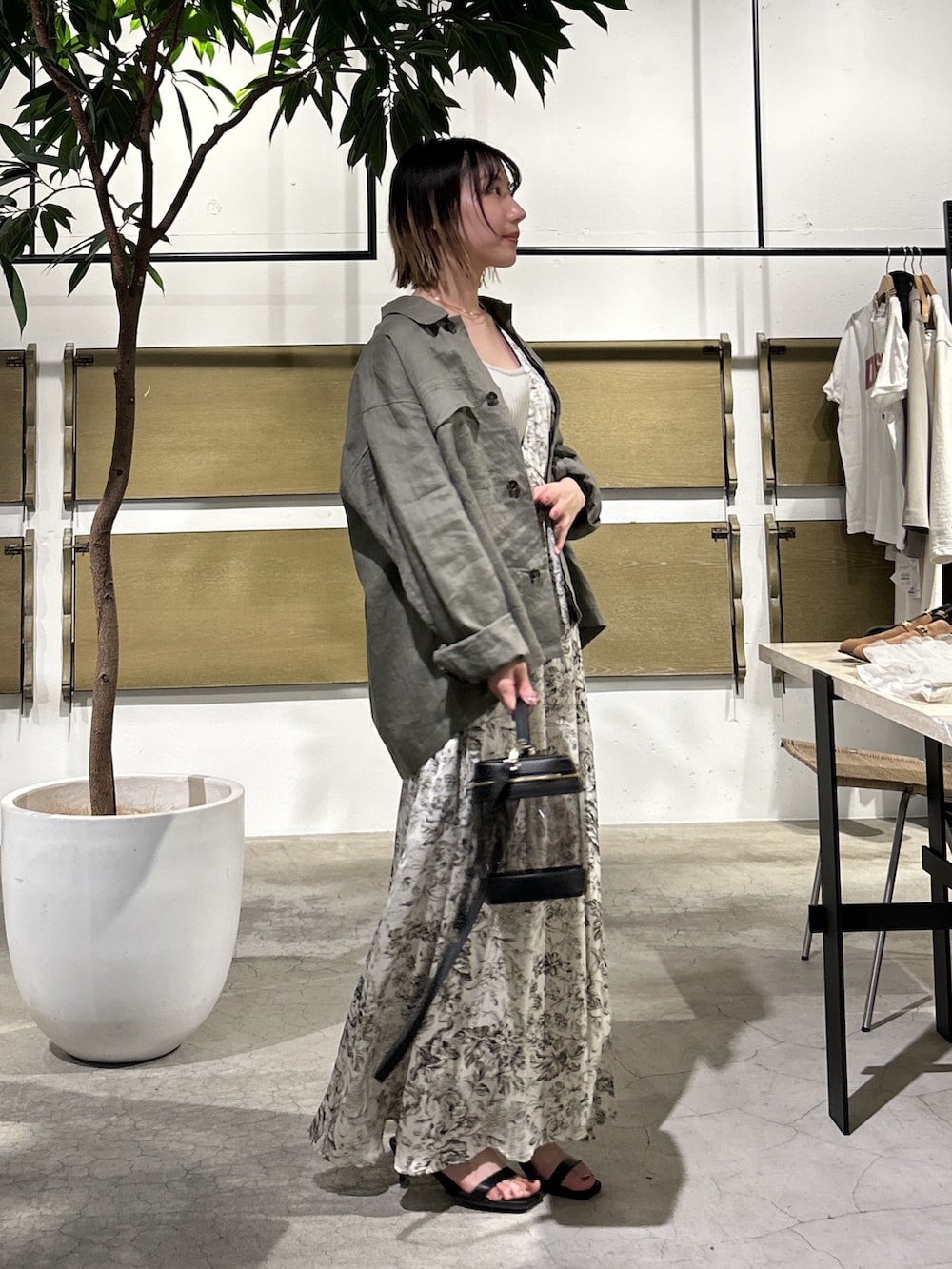 ホワイト系のワンピース、グリーン系のベスト、ブラック系のショルダーバッグを着用したレディースの春コーディネートの2枚目の写真