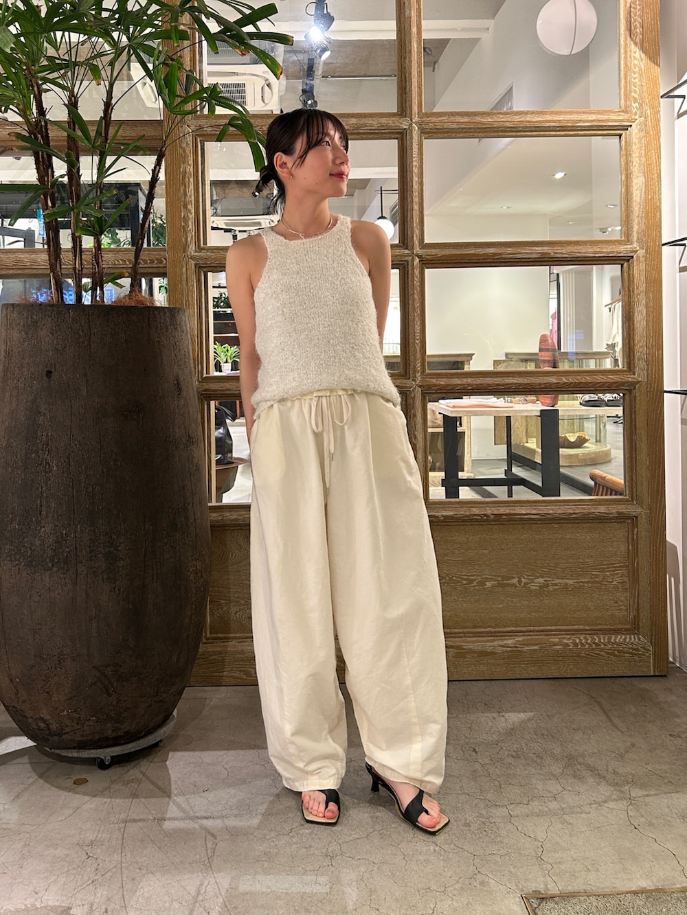 ホワイト系のニット/セーター、ホワイト系のその他パンツ、ブラック系のサンダルを着用したレディースの夏コーディネートの2枚目の写真