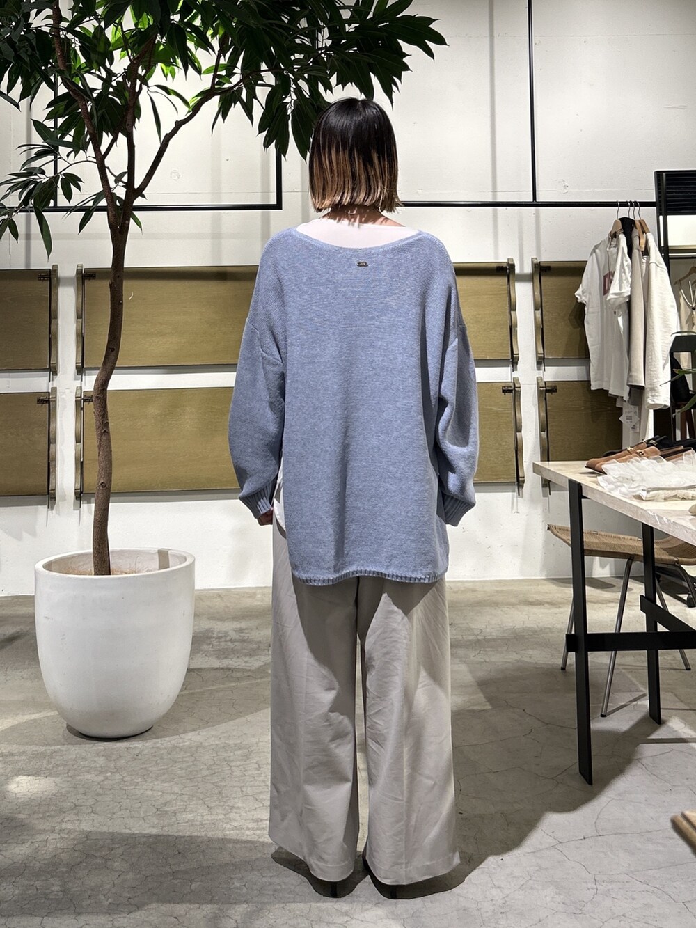 ブルー系のニット/セーター、ホワイト系のシャツ/ブラウス、グレー系のその他パンツを着用したレディースの春コーディネートの2枚目の写真