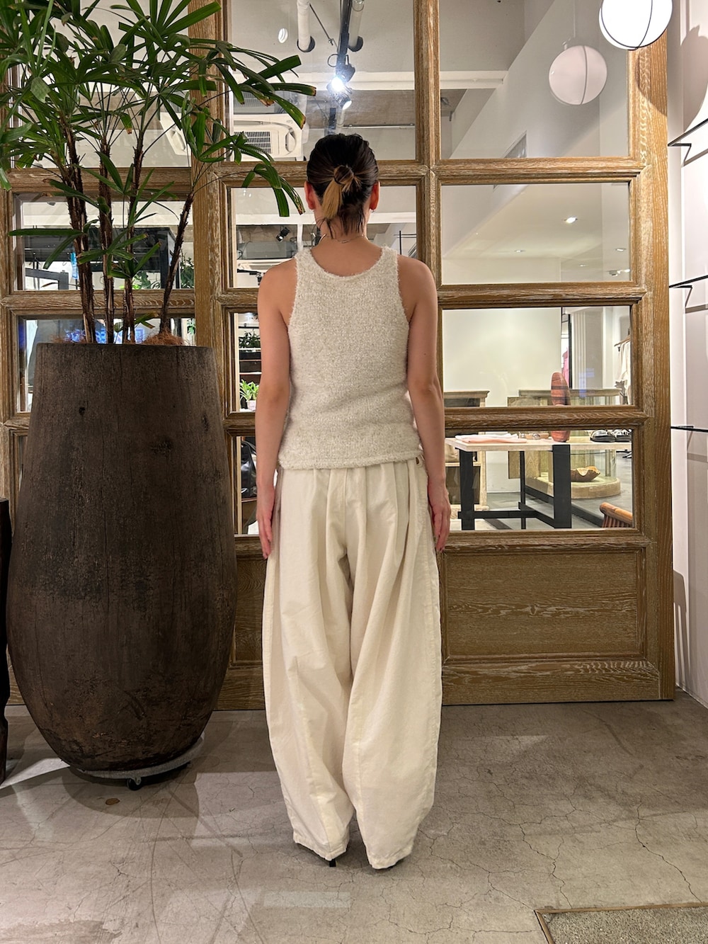 ホワイト系のニット/セーター、ホワイト系のその他パンツ、ブラック系のサンダルを着用したレディースの夏コーディネートの4枚目の写真