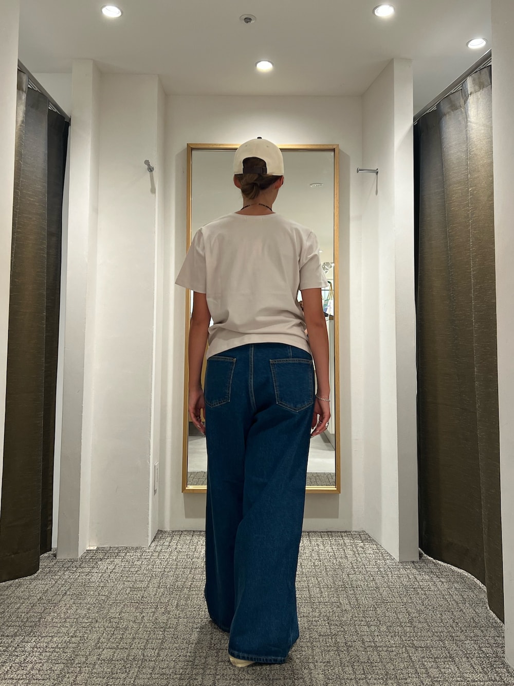 ブルー系のデニムパンツ、ベージュ系のTシャツ/カットソー、ベージュ系のスニーカーを着用したレディースの夏コーディネートの3枚目の写真