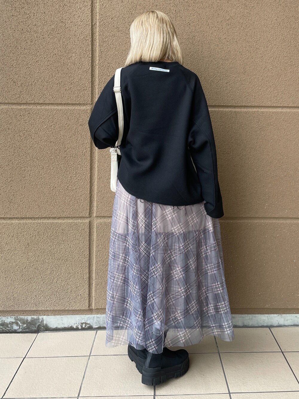 ブラック系のスウェット、ブルー系のスカート、レッド系のショルダーバッグを着用したレディースの秋コーディネートの2枚目の写真