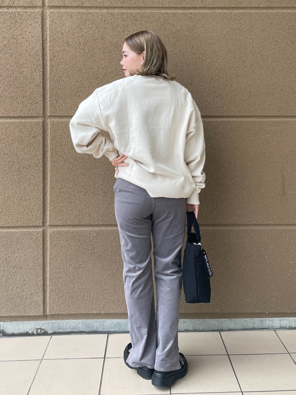 ブラック系のショルダーバッグ、ホワイト系のスウェット、グレー系のその他パンツを着用したレディースの冬コーディネートの2枚目の写真
