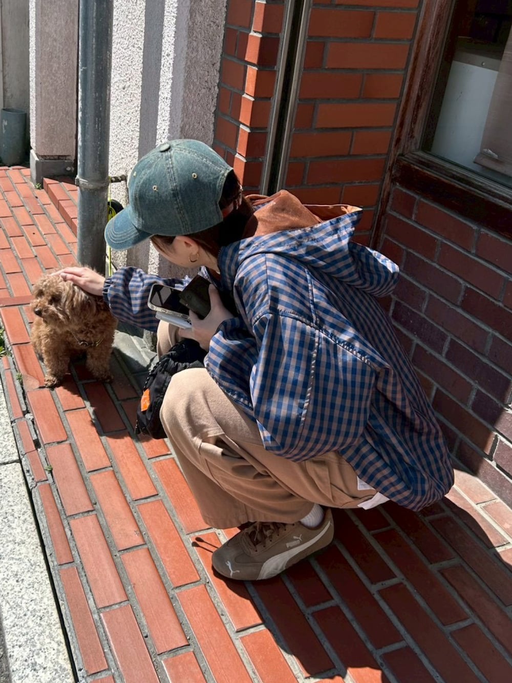 ブルー系のパーカー、ベージュ系のデニムパンツ、ブラウン系のスニーカーを着用したレディースの春コーディネートの2枚目の写真