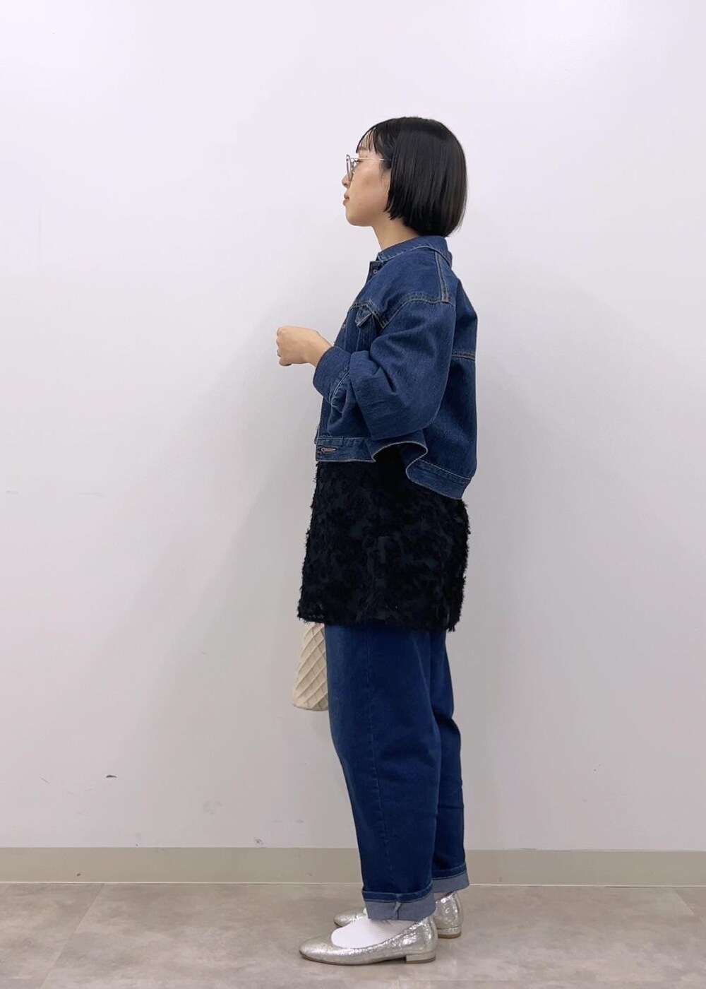 ブラック系のキャミソール、ブルー系のデニムジャケット、ホワイト系のTシャツ/カットソーを着用したレディースの冬コーディネートの3枚目の写真