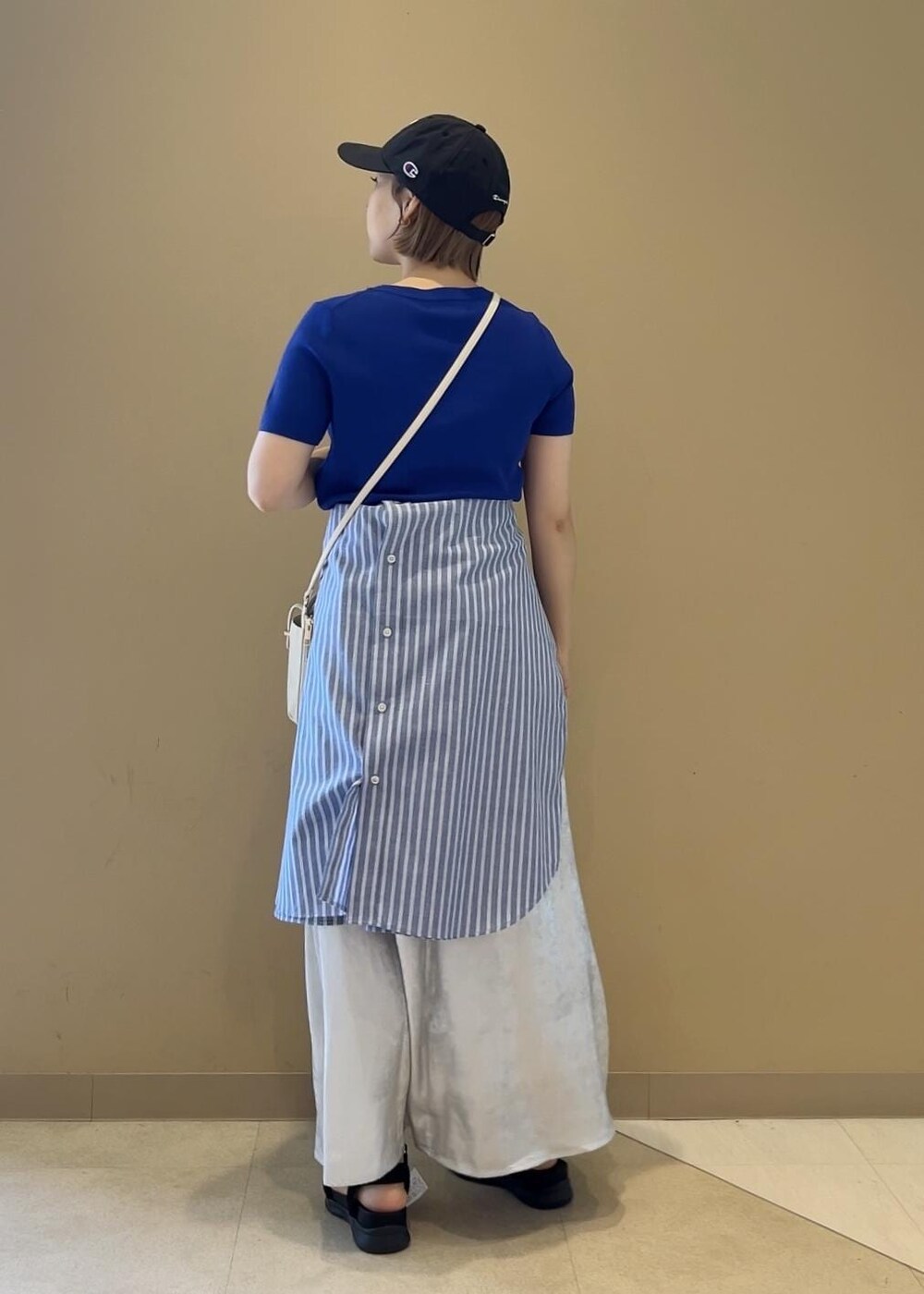 シルバー系のスカート、ブルー系のニット/セーター、ブラック系のサンダルを着用したレディースの夏コーディネートの2枚目の写真