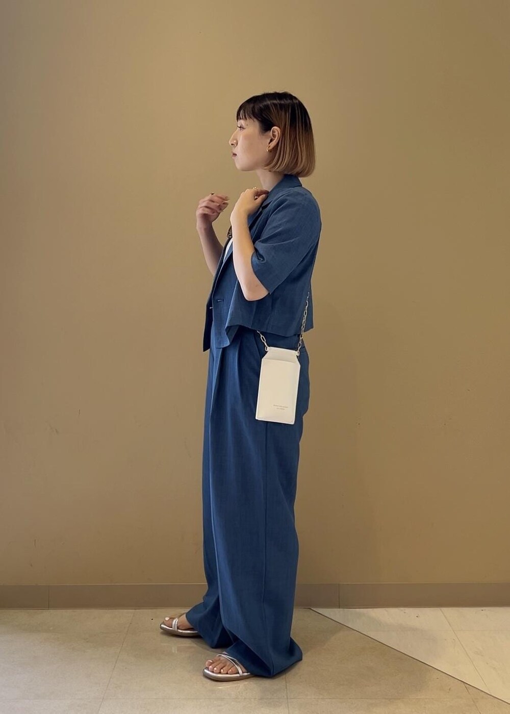 シルバー系のサンダル、ホワイト系のショルダーバッグ、ホワイト系のTシャツ/カットソーを着用したレディースの春コーディネートの2枚目の写真
